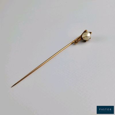 a close up of a gold pin with a pearl on it