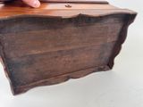 a hand that is holding a wooden box on a table