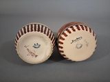 pair of baseballs with signed signatures on them sitting on a gray surface