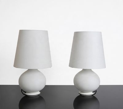 two white lamps on a black table with a white lamp shade