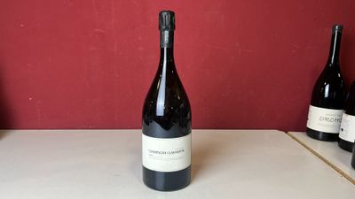 trois bouteilles de vin sont posées sur une table devant un mur rouge