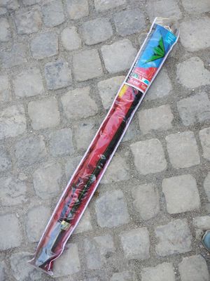 Une personne se tient sur le trottoir à côté d'un parapluie emballé dans du plastique.