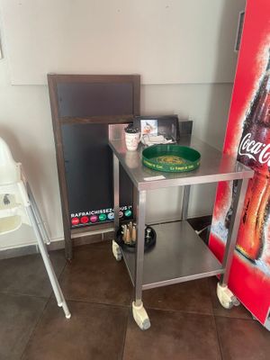 une chaise haute à côté d'une table sur laquelle est posée une affiche Coca-Cola