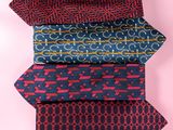 four ties stacked on top of each other on a pink background