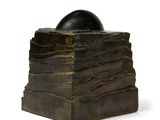 une sculpture représentant une balle posée au sommet d'une pile de livres