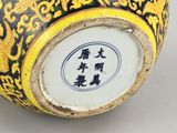 a yellow and black vase with asian writing on it