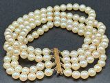 pearl necklace with a gold clasp on a black surface