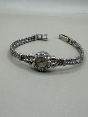 bracelet en argent orné d'une montre, posé sur un fond blanc