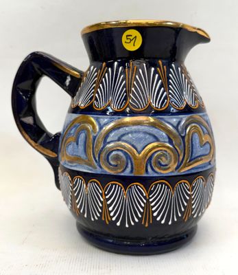 un vase bleu et or muni d'une anse noire