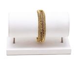 un gros plan d'un bracelet posé sur un présentoir, sur une surface blanche