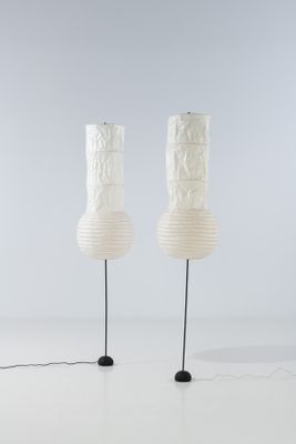 une paire de lampes en papier blanc montées sur des pieds en métal noir