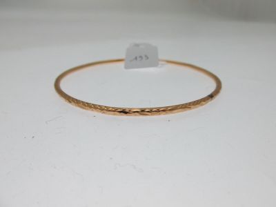 gros plan d'un bracelet en or sur une surface blanche