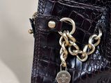 purple crocodile skin purse with a chain and a silver ring