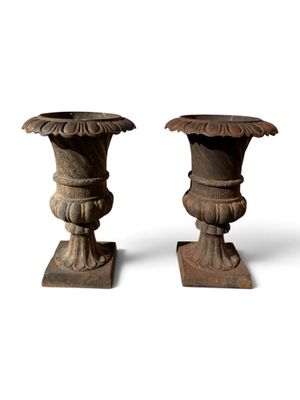 une paire de vases anciens en bois posés sur des socles, sur fond blanc