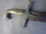 a metal object that looks like a sword on a piece of wood