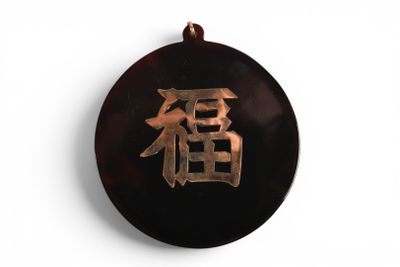 une photo d'un pendentif sur lequel figure un caractère chinois