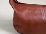 brown leather purse on a white table with a white background