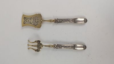 deux cuillères en argent et une cuillère à manche, posées sur une surface blanche