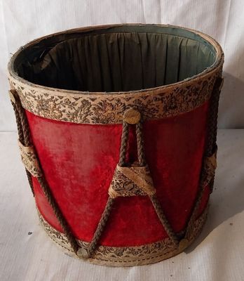 un tambour rouge et doré posé sur une surface blanche