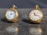 two gold pocket watches sitting on top of a table