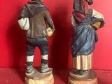 two figurines of a man and a woman standing next to each other on a red surface