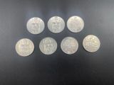 six silver coins of different sizes and shapes on a black surface