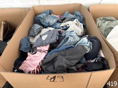 a cardboard box full of clothes sitting on the ground