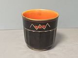 une tasse noire et orange posée sur une table