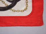 a picture of a red and white scarf with a black and gold chain on it