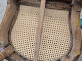 an old wooden chair with a wicker seat on the floor