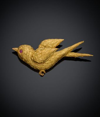 une image représentant une broche en forme d'oiseau doré sur fond noir