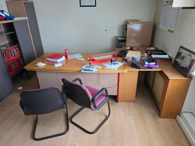 a desk with two chairs and a book shelf in the corner