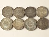 six pièces de monnaie britanniques différentes sont disposées en ligne sur une surface blanche