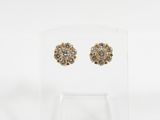 a pair of gold tone earrings on a clear acrylic stand