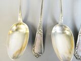 three silver spoons and two silver spoons on a gray surface