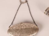 a silver purse hanging on a chain next to a cup