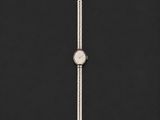 une montre argentée posée sur une surface noire avec un fond noir