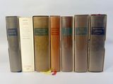 several books are lined up in a row on a white surface