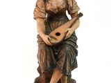 statue of a woman with a guitar sitting on a rock
