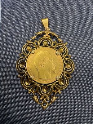 un pendentif en forme de pièce d'or sur lequel est représenté un homme