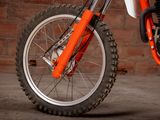 an orange dirt bike parked in front of a brick wall