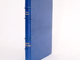 an old blue book sitting on top of a table next to a white wall