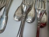 several spoons and forks are lined up on a table