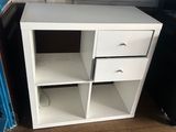 a white desk with two drawers and a black refrigerator
