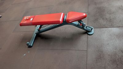 a red bench sitting on the floor in a gym