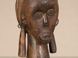 une vieille sculpture en bois représentant la tête d'une femme portant des boucles d'oreilles