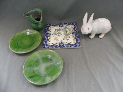 une figurine de lapin blanc posée à côté d'une assiette et d'un bol verts