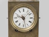 une petite horloge en laiton avec des chiffres romains sur le cadran