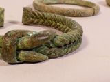 several pieces of ancient bronze bracelets on a white surface