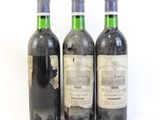 trois bouteilles de vin posées les unes à côté des autres sur une surface blanche